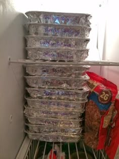 a refrigerator filled with lots of silver foil wrapped in plastic wrap and some food on top of it