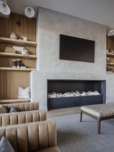 a living room filled with furniture and a flat screen tv mounted on the wall above a fire place