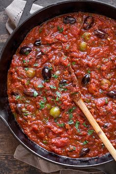 a skillet filled with tomato sauce and olives