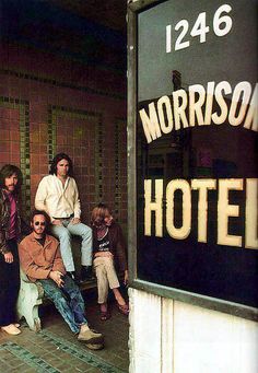 some people sitting on a bench in front of a hotel sign