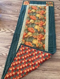 a quilted table runner on top of a wooden floor next to a pot holder