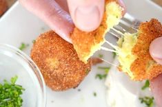 a person holding a fork with some food in it and dipping sauce on the side