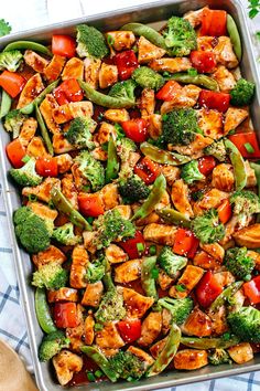 a pan filled with tofu and broccoli on top of a blue table cloth