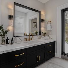 a bathroom with double sinks, mirrors and lights on the wall next to large windows