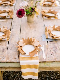 a wooden table topped with plates and place settings