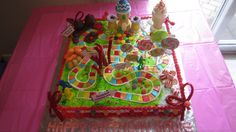 a birthday cake decorated with candy and candies on a pink tableclothed table