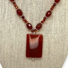 This is a beautiful, red carnelian beaded pendant choker. Oval and round carnelian beads are separated by sterling caviar-style beads on the estate necklace. The pendant is a rectangular red carnelian. This semi-precious gemstone symbolizes health, luck, and royalty. It is a variety of the silica mineral chalcedony colored by impurities of iron oxide. The necklace fastens with a silver toggle clasp. Brand: Unknown Markings: Unmarked metal; this item has been tested to confirm metal content. Mate Red Beaded Necklaces, Red Carnelian, Multi Gemstone Ring, Pendant Choker, Carnelian Beads, Beaded Pendant Necklace, Beaded Hoop Earrings, Beaded Hoops, Hand Jewelry