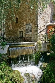 a small waterfall in front of a stone building