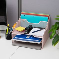 a desk with a computer monitor, pen holder and various office supplies on top of it