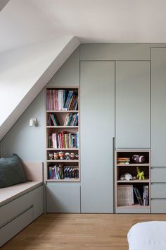 an attic bedroom with built in bookshelves and storage