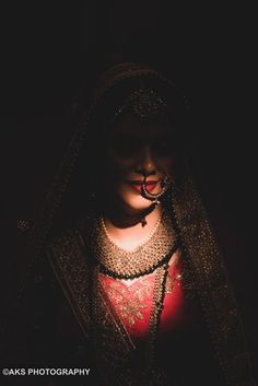 a woman wearing a veil and jewelry in the dark