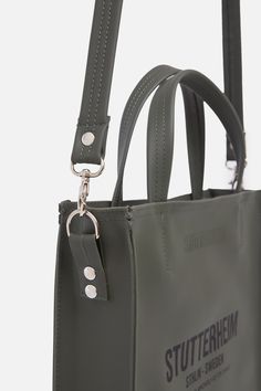 Djursholm is a slim rectangular tote bag crafted in dense and sturdy waterproof fabric, perfectly sized to fit a laptop as well as essential items such as a phone, wallet etc. This elegant piece can be worn as a crossbody bag with the attachable shoulder strap or carried by hand by the top handles. A metal zipper at the top opening keeps belongings safe while the Cordura membrane ensures durability. Craft Tote Bag, Bag Dark, Bag Green, Logo Label, Essential Items, Zipper Top, Phone Wallet, Metal Zipper, Rain Wear