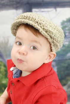 a young boy wearing a crocheted hat and red shirt