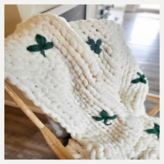 a crocheted blanket with shamrocks on it sitting on a wooden rocking chair