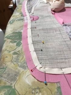 the table is covered with pink and white fabric, along with several different colored pins