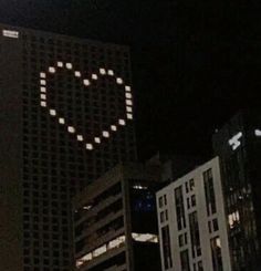 a smiley face is projected on the side of a tall building in a city at night