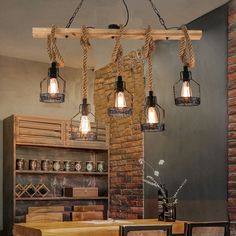 a dining room table with chairs and lights hanging from it's beams in front of a brick wall