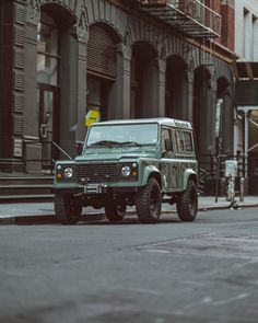 an old green jeep is parked on the street