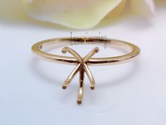 a close up of a gold ring on a white surface with a rose in the background