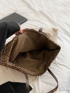 a woman holding a brown purse on top of a bed