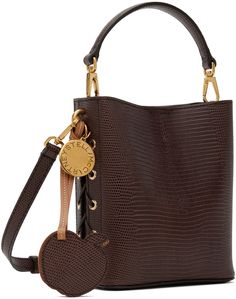 Croc-embossed UPPEAL™️ faux-leather shoulder bag in brown. · Detachable carry handle · Adjustable and detachable shoulder strap · Lace-up detailing at sides · Logo tag and disc at side · Magnetic closure · Patch pocket at interior · Faux-suede recycled nylon lining · Gold-tone hardware · H6.75 x W5.75 x D3 Made from cruelty-free, non-animal materials. Supplier color: Chocolate brown Luxury Brown Shoulder Bag With Round Handle, Luxury Brown Bucket Bag With Detachable Strap, Luxury Brown Bucket Bag With Detachable Handle, Brown Textured Leather Top Handle Bucket Bag, Luxury Brown Textured Leather Bucket Bag, Stella Mccartney Frayme, Embossed Bag, Color Chocolate, Logo Tag