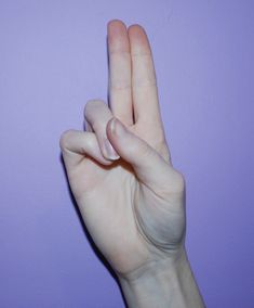 a person's hand making the number one sign with their fingers against a purple background