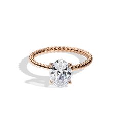 a rose gold ring with a white diamond in the center and a rope band around it