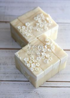 two pieces of soap sitting on top of a white wooden table next to each other