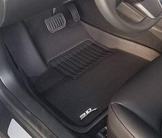 the interior of a car with black leather seats and floor mats, including an automatic steering wheel