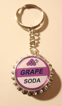 a bottle cap keychain with the word grape soda on it's side