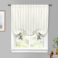 a window with a white curtain hanging from it's side and a potted plant next to it