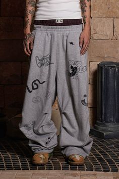 The Graffiti Crinkled Wide-Leg Sweatpants perfectly merge street style with a playful, artistic flair. These sweatpants are adorned with an all-over print of quirky graffiti graphics, adding a vibrant and dynamic touch to the design. The double-waist elastic band provides a unique and comfortable fit, while the crinkled texture along the legs enhances the visual appeal. The back features curved stitching for added dimension, making these pants as stylish as they are comfortable. Crafted from pre Baggy Graphic Print Bottoms For Streetwear, Casual Graphic Print Pants For Streetwear, Casual Oversized Bottoms With Graphic Print, Urban Graphic Print Spring Pants, Baggy Streetwear Pants With Graphic Print, Graphic Print Trousers For Streetwear, Baggy Graphic Print Pants For Streetwear, Hip Hop Wide Leg Bottoms With Graphic Print, Hip Hop Graphic Print Relaxed Fit Bottoms