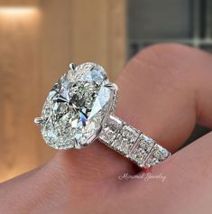 a close up of a person's hand holding a diamond ring