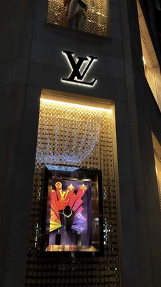 a person standing in the window of a louis vuitton store at night time