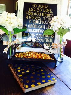 two vases filled with flowers sitting on top of a table next to a sign