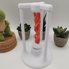 there is a small white candle holder next to some succulents and plants