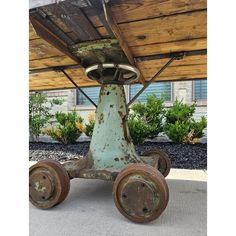 an old rusted metal cart sitting under a wooden roof in front of a house