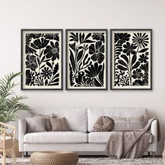 two black and white paintings on the wall above a couch