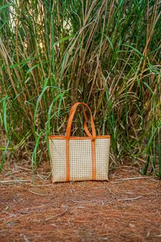 Our Bella rattan and leather trim tote is a classic fun way to complete any look this season. Our handbags are all handmade. Want to add a little something special to your handbag? Accessorize with our 100% silk scarves. Ready to ship! Please allow 1-2 business days to process your order and ship. Details: Rattan Leather trim Handmade Made in Indonesia 14.75” (L) x 11.5” (W) x 12” (H) Rattan Tote Bag With Woven Leather, Woven Leather Rattan Tote Bag, Rectangular Tan Straw Bag With Leather Handles, Rectangular Rattan Bag With Woven Leather, Rectangular Rattan Bags With Woven Leather, Tan Straw Bag With Double Handle, Leather Straw Bag With Bamboo Handle For Shopping, Tan Woven Leather Bag For Everyday Use, Tan Straw Bag With Leather Handles For Shopping