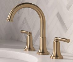 a gold faucet on a white marble counter top