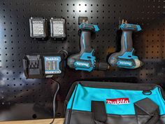 two cordless drillers and one power tool are on the wall with other tools