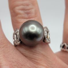 Beautiful Ring Set In 18k White Gold That Features An Approx 13mm Tahitian Black Pearl Surrounded By .53 Ctw Of Round Diamonds! This Ring Is Size 6 And Weighs 9.5 Gm. The Pearl Is High Luster With Some Natural Blemishes And Is Grey/Black/Purple In Color. There Are 18 Round Diamonds On Each Side Of The Band For A Total Carat Of .53. Color H Clarity Si1. It Is Stamped 750 (18k) And 053 On The Interior Of The Band. It Is A Lovely Estate Ring That Has Been Well Cared For! It Comes With A Recent Gia Appraisal For $3,250!! Luxury Tahitian Pearl Jewelry With Brilliant Cut, Formal White Gold Jewelry With Tahitian Pearl, White Gold Tahitian Pearl Jewelry With Diamond Accents, White Gold Tahitian Pearl Jewelry With High Luster, White Gold Tahitian Pearl Jewelry For Anniversary, Tahitian Pearl White Gold Jewelry With Diamond Accents, Elegant White Gold Tahitian Pearl Ring, Fine Jewelry With Tahitian Pearl And Diamond Accents, Luxury Tahitian Pearl Jewelry With Diamond Accents