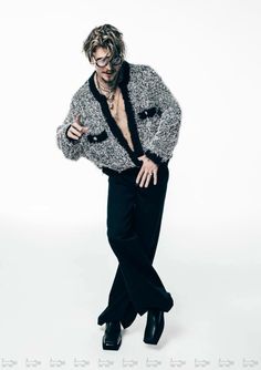 a man with glasses and a sweater is posing for a photo in front of a white background