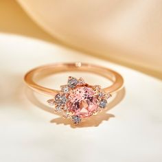 100% recycled precious metal Set in the center with a lovely approx. 1.25ct (6mm) round cut lab grown rosé sapphire. With a blush hue reminiscent of the color of morganite, our rosé sapphire features a slightly more saturated pink, and it offers a much better durability than morganite, making it ideal for an engagement ring! Available in two different tones: a hint of peach, or a hint of lilac One of a kind asymmetrical cluster halo featuring sparkly colorless lab grown diamonds, peppered with m Pink Diamond Gold Engagement Ring, Pink Cluster Ring With Round Cut, Pink Cluster Ring With Halo Setting, Pink Cluster Ring With Center Stone, Pink Round Cluster Ring With Prong Setting, Rose Gold Pink Sapphire Ring For Wedding, Rose Gold Pink Sapphire Wedding Ring, Wedding Rose Gold Pink Sapphire Ring, Rose Gold Brilliant-cut Diamond Sapphire Ring