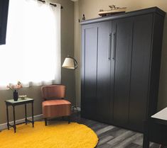 a room with a yellow rug and black cabinet