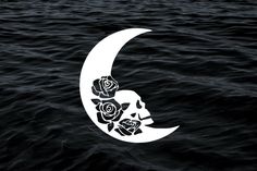 a white moon with roses on it floating in the dark blue water next to an ocean