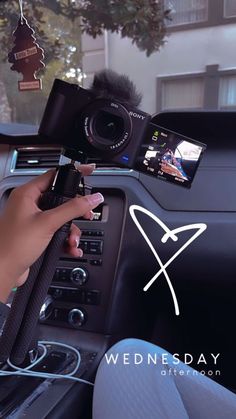 a person holding a camera in their hand while sitting in the driver's seat of a car