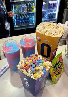 popcorn, drinks and candy are on the table