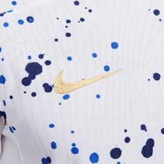 the back of a white nike shirt with blue and yellow spots on it's chest