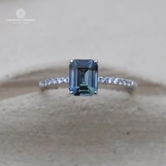 an emerald colored diamond ring with diamonds around it